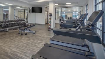 Un gimnasio con cintas de correr, mancuernas y pelotas de ejercicio.