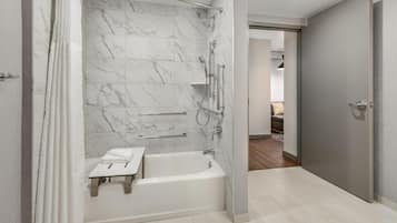 A modern bathroom with a marble shower wall, a bathtub, and a vanity with a towel rack.