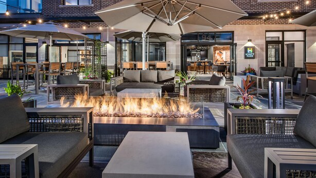 An outdoor seating area with fire pits, umbrellas, and modern furniture. - Hyatt Place Newark - Main Street (Newark)