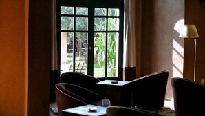 A room with a large arched window, a table, two chairs, and a lamp. - Villa Al Assala La Palmerale (Marrakech)