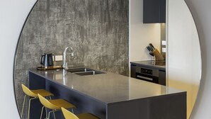 A modern kitchen with a central island, bar stools, and a textured backsplash. - Laid back living with city views (Auckland)