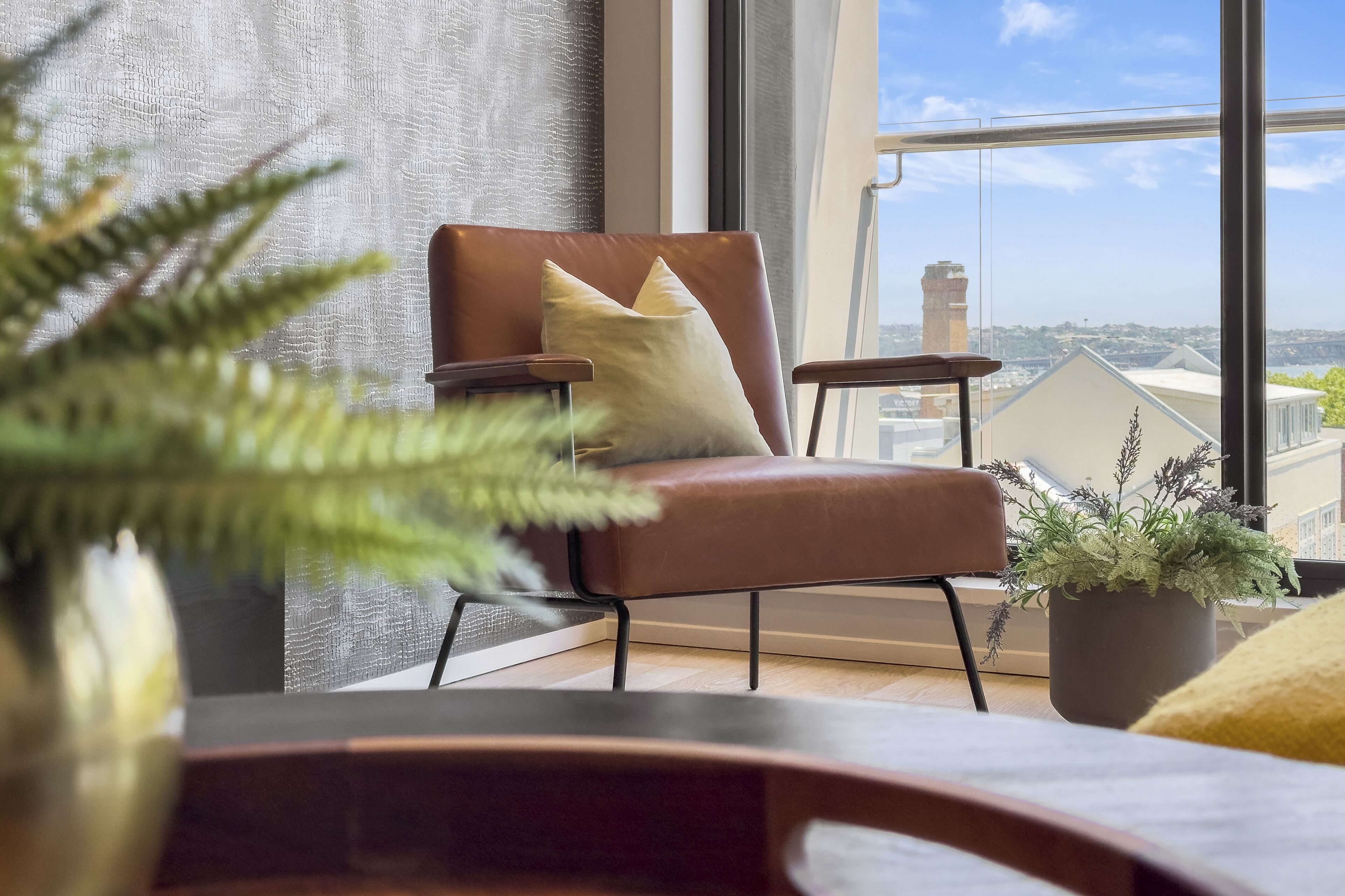 A modern living room with a leather armchair, a small side table, and a potted plant.