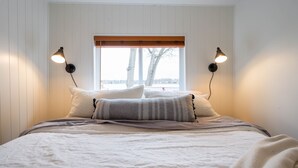 Une chambre à coucher avec un grand lit, deux lampes de chevet et une fenêtre donnant sur des arbres.