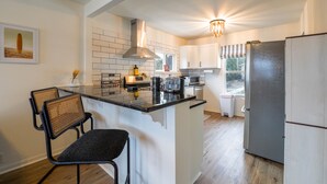 Une cuisine moderne dotée d’un îlot central, de meubles blancs et d’un réfrigérateur en acier inoxydable.