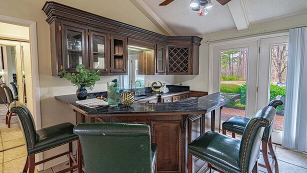 A kitchen with dark wooden cabinets, a marble countertop, and a central island with bar stools. - Waterfront Paradise with Golf Course Views (Florence)