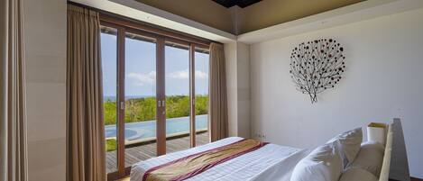 A bedroom with a large bed, a view of a pool, and a ceiling with wooden beams.