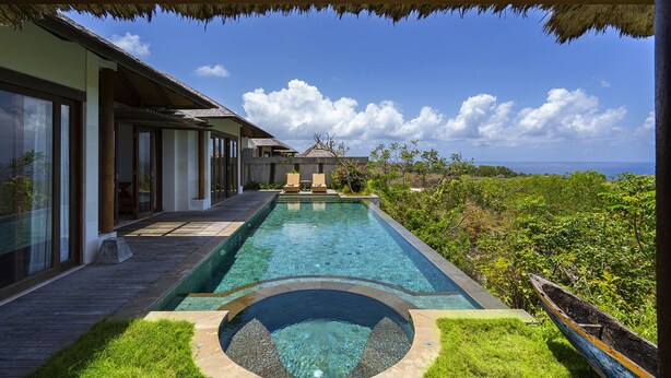 A swimming pool with a circular hot tub, a wooden deck, and a view of the ocean. - Moritz Palm Villa (Kutuh)