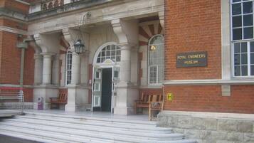 The entrance to the Royal Engineers Museum with a sign, steps leading up to the entrance, and benches outside.