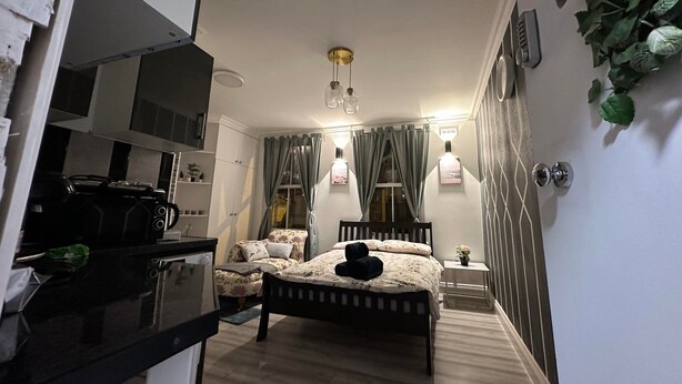 Ein gemütliches Schlafzimmer mit Bett, Nachttisch und einem kleinen Fenster mit Vorhängen.