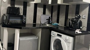 Eine kleine Küche mit Mikrowelle, Toaster, Kaffeemaschine und Waschmaschine.