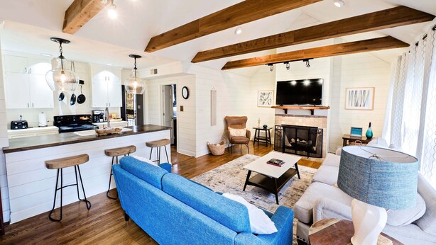 A modern kitchen with white cabinets, a central island with stools, and a dining area with a sofa and a TV. - Charming Three Bdrm Home on Quiet Street- Near U of M - Fully Fenced Yard- (Memphis)