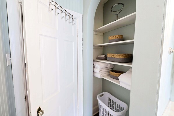 Une buanderie avec une porte blanche, des étagères avec des paniers et un panier à linge.