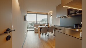 A modern kitchen with a dining area, large windows, and a view of the city. - City Center Premium Apartment by Vacationy (Porto)