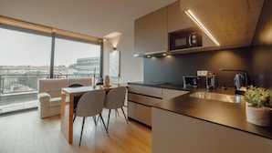 A modern kitchen with a large window, a dining area with a sofa and chairs, and a view of the city. - City Center Premium Apartment by Vacationy (Porto)