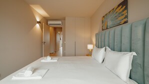 A hotel room with a large bed, a headboard, a painting on the wall, and an air conditioning unit. - City Center Premium Apartment by Vacationy (Porto)