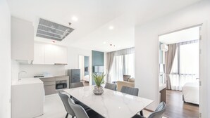 Moderni hotellihuone, jossa on ruokailutila, pieni keittiö ja suuri sänky.