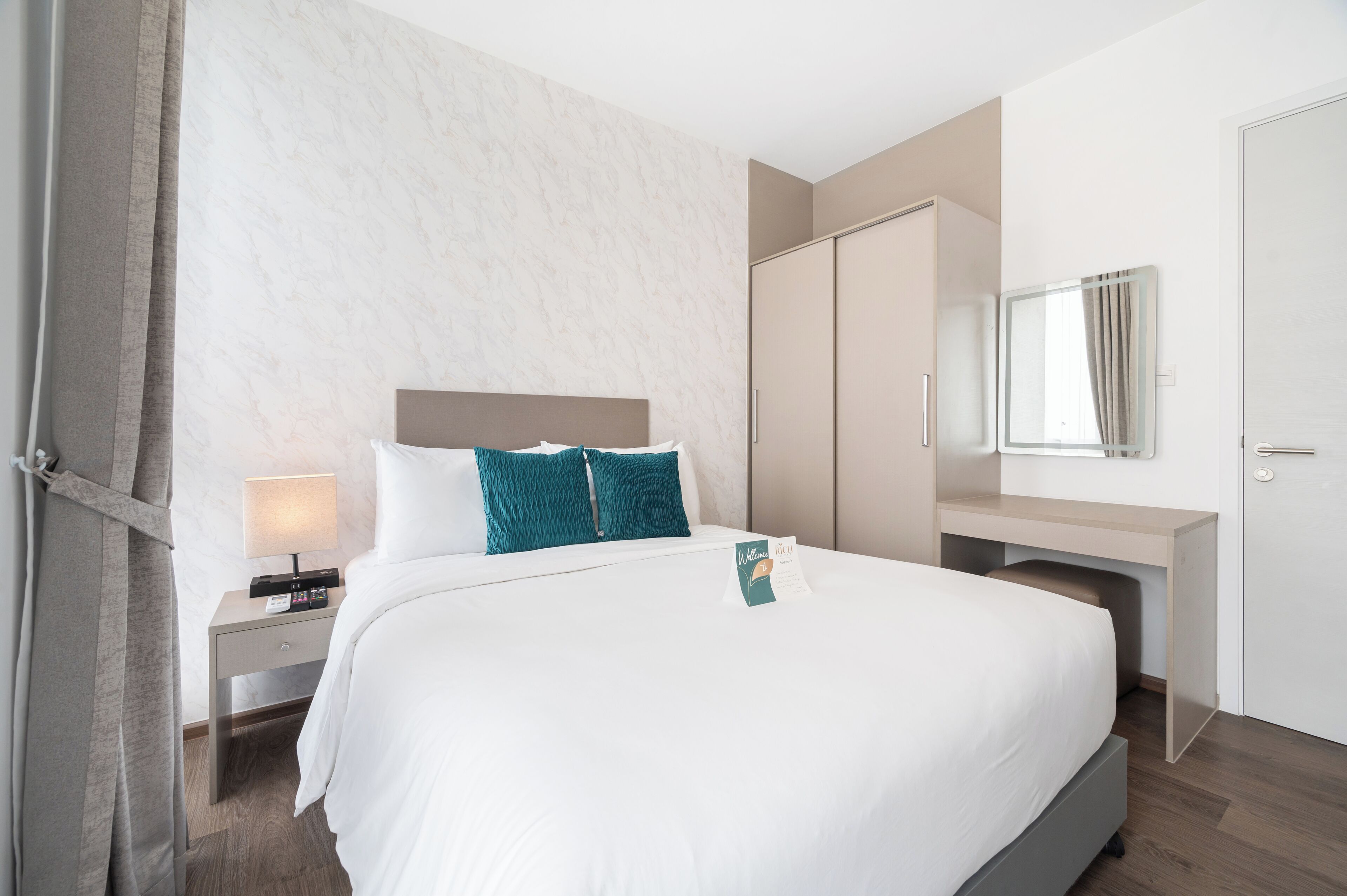 Hotellihuone, jossa on suuri sänky, työpöytä, vaatekaappi ja peili.