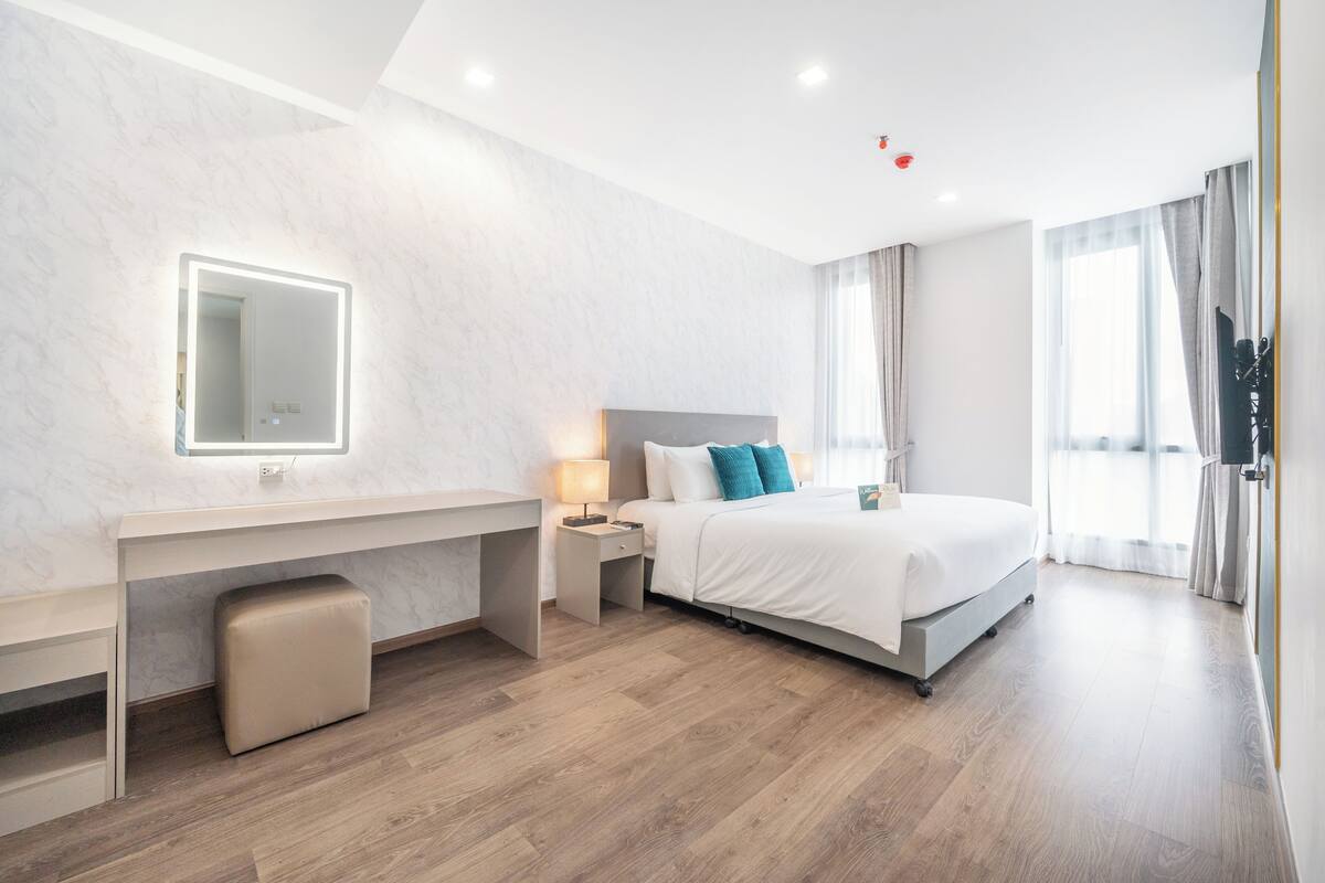 Ein modernes Hotelzimmer mit Bett, Schreibtisch und einem großen Spiegel.
