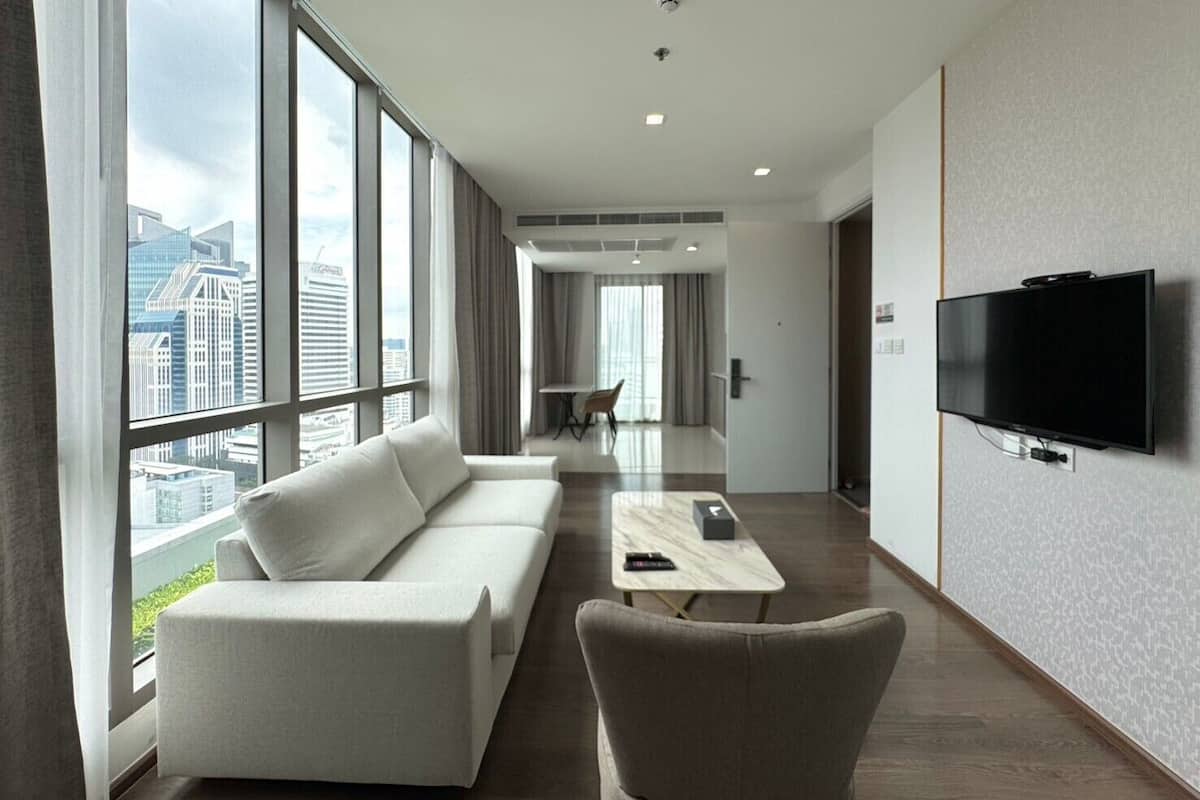 Ein modernes Hotelzimmer mit einer Couch, einem Sessel und einem flachbildfernseher an der Wand.