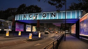 A street scene with a large illuminated sign reading "ACTON" above the road. - Fabulous Apartment to Acton Town (London)