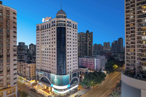 A high-rise hotel with a prominent dome and signage, surrounded by other tall buildings in an urban setting.
