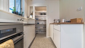 Een keuken met witte kastjes, een Bosch oven en een inbouwvoorraadkast.
