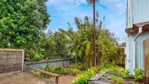 A wooden deck leading to a garden area with raised beds and a variety of plants.