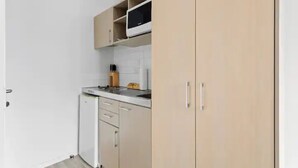 A compact kitchen with a microwave, a sink, and a small refrigerator. - Central City 1Br Apartment (Auckland)