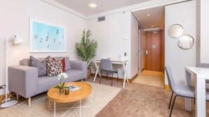Un salon moderne avec un canapé gris, une table basse, une petite plante et un bureau avec une chaise.