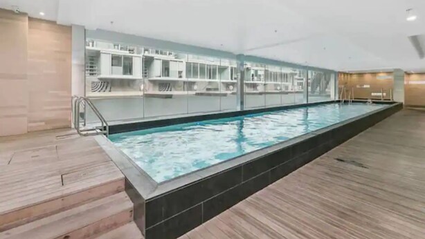 A large indoor swimming pool with a tiled floor and a glass wall on one side.