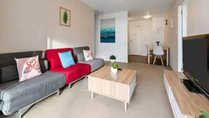A modern living room with a grey sofa, a red throw blanket, and a wooden coffee table.