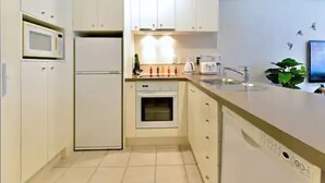 Una cucina moderna con mobili bianchi, un forno a microonde, una lavastoviglie e un lavello.