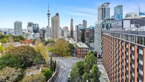A cityscape with modern high-rise buildings, a prominent tower, and a bridge. - Stunning Sky Tower View Studio Pool And Gym! (Auckland)