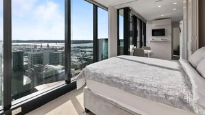 Una camera da letto moderna con un letto grande, una televisione e vista sulla città.