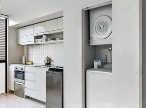 Fully equipped kitchen with oven, dishwasher, and kettle.