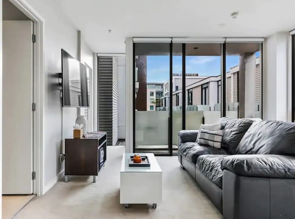 Relax in this stylish living room with a sleek sofa, coffee table, and balcony access.