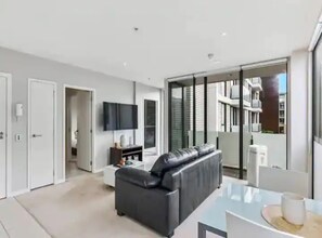 Relax in a comfortable seating area with a large sofa, flat-screen TV, and glass coffee table.