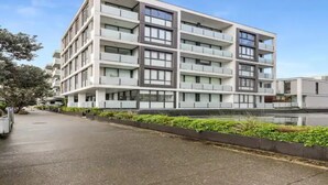 A modern multi-story building with a flat facade, large windows, and a clean, organized exterior. - Lovely And Cozy Apartment - Parking, Pool And Gym! (Auckland)