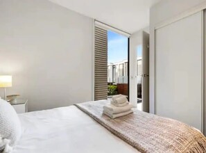 Enjoy a restful stay in this stylish room with a comfortable bed, bedside table, and balcony access.