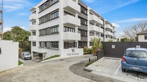 A modern multi-story residential building named "The Ridge" with a parking area in front. - Convenient Modern 2-Bedroom Unit With Free Parking (Auckland)