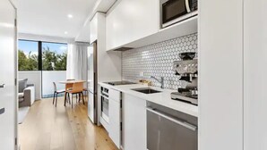 A modern kitchen with a microwave, espresso machine, and a hexagonal tile backsplash. - Convenient Modern 2-Bedroom Unit With Free Parking (Auckland)
