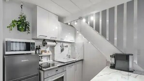Una cocina moderna con electrodomésticos de acero inoxidable, armarios blancos y una encimera de mármol.