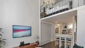 Una sala de estar moderna con un cuadro abstracto de gran tamaño, una consola de madera, una mesita redonda y un sofá color turquesa.