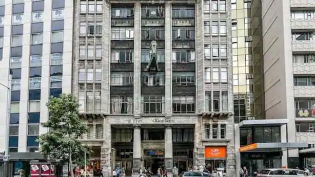 Un edificio de varios pisos con un estilo arquitectónico clásico, que presenta una entrada central con un gran arco y columnas.
