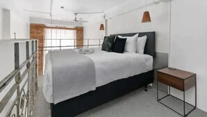 Un dormitorio moderno con cama, mesita de noche y vistas a un balcón.