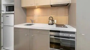 A modern kitchen with stainless steel appliances, a kettle, and a microwave. - Stunning Spacious Studio In Viaduct Basin (Auckland)