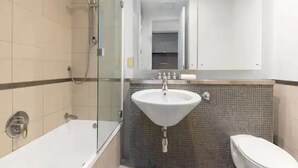 A modern bathroom with a glass-enclosed shower, a white sink, and a toilet. - Stunning Spacious Studio In Viaduct Basin (Auckland)
