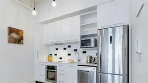 A modern kitchen with stainless steel appliances, white cabinetry, and a brown rug. - Stylish studio near Spark Arena I Zodiak Stays (Auckland)