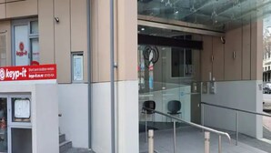 A building entrance with a glass door, a sign for 'keyp-it' short-term lockbox rentals, and a metal handrail leading to the entrance. - Central Modern Apt. w/ Working Space Zodiak Stays (Auckland)