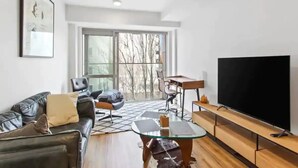 A modern living room with a sofa, a glass coffee table, a TV, and a large window. - Central Modern Apt. w/ Working Space Zodiak Stays (Auckland)